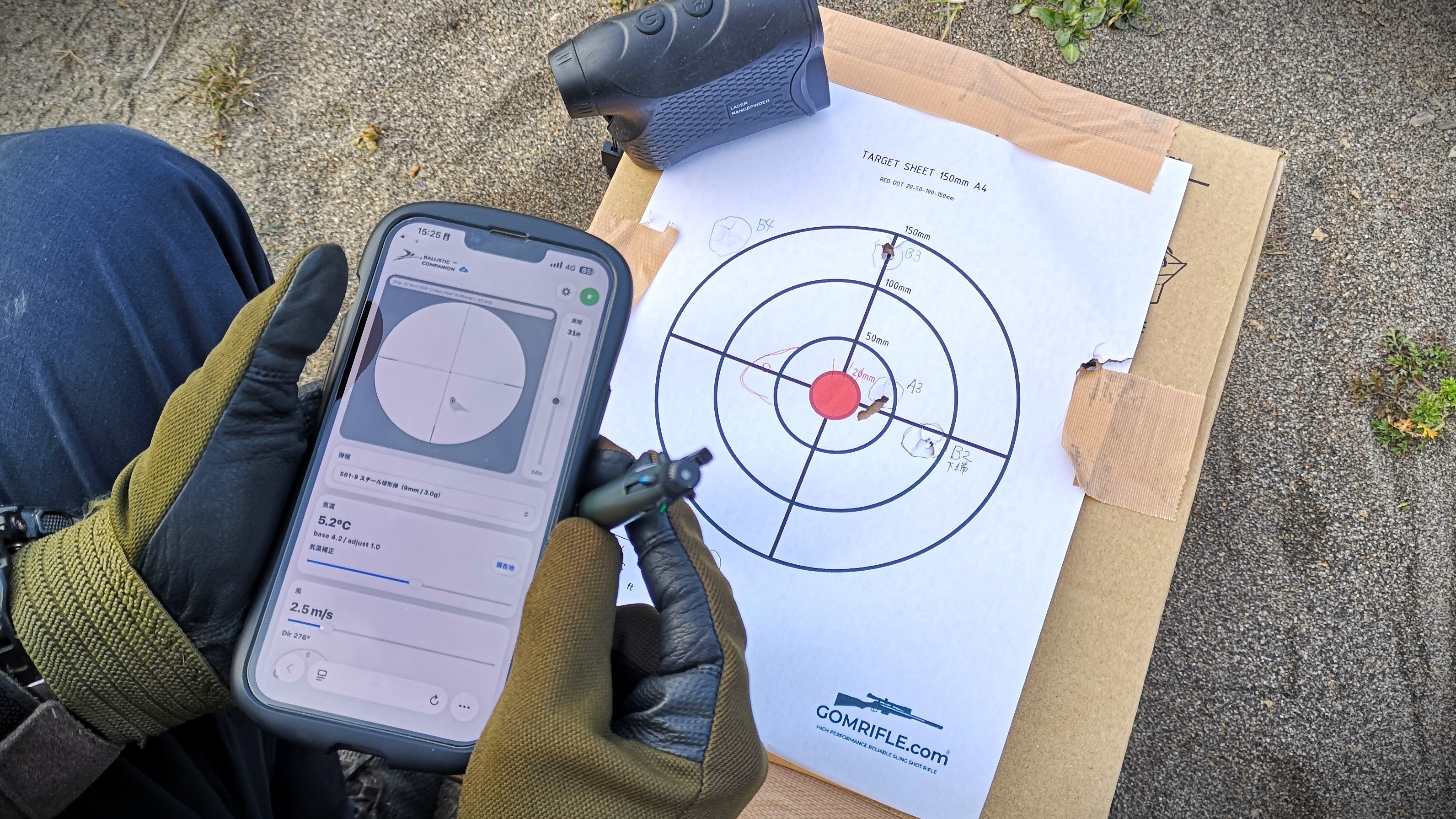 フィールドで BALLISTIC COMPANION を表示したスマートフォンと、レンジファインダー・GOMRIFLE.com 公式ターゲットシート